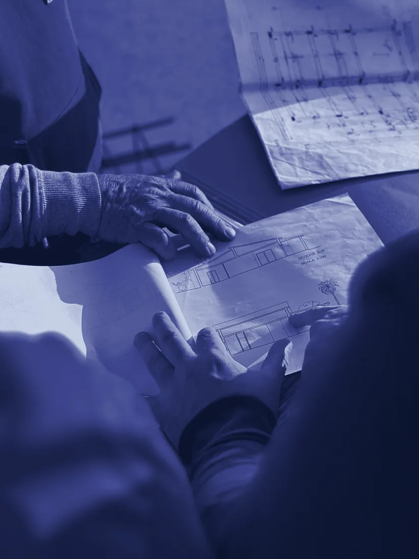 Hands reviewing site plans on a table, deciding where to invest
